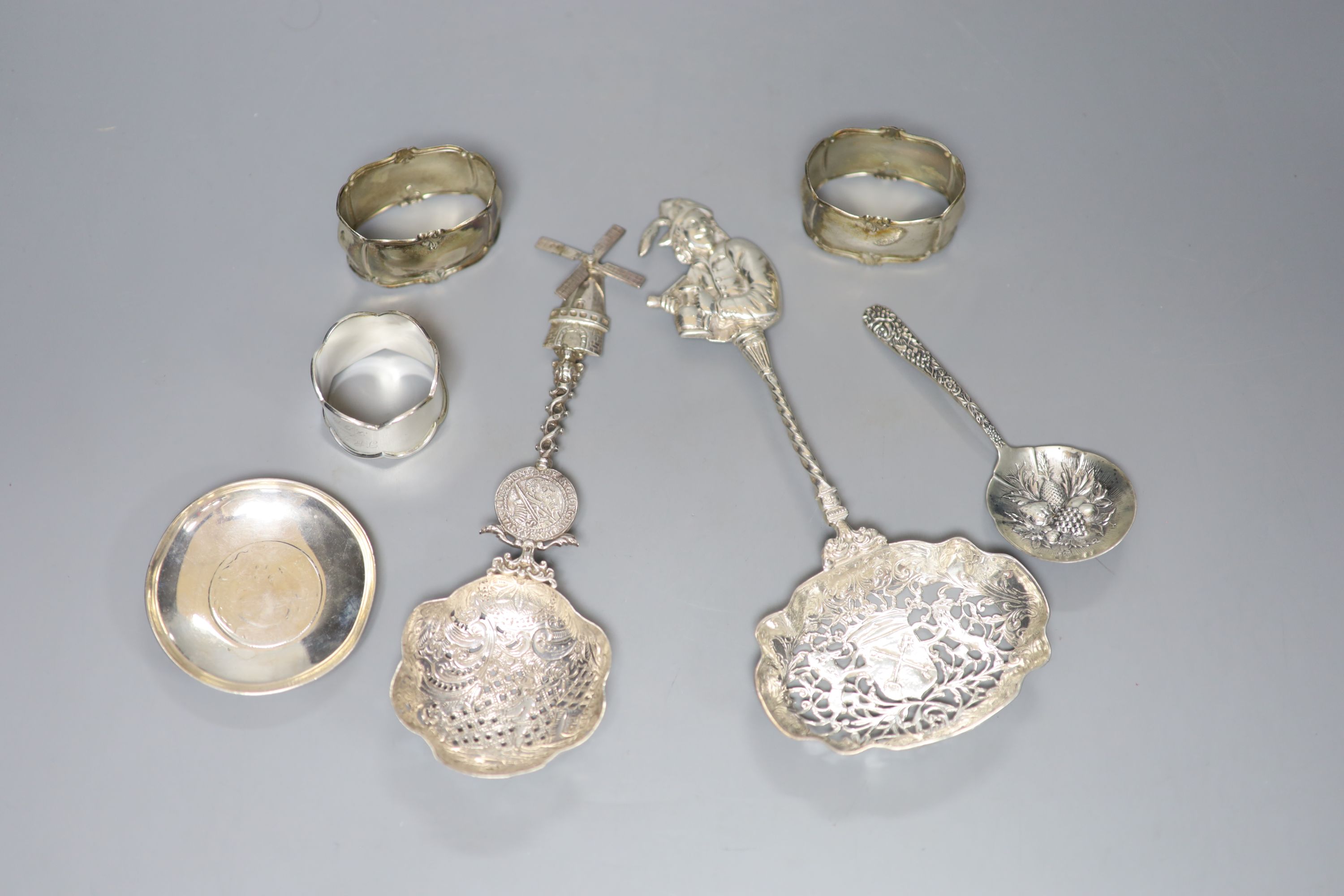 Two late 19th/early 20th century ornate pierced silver spoons, largest 23.7cm, a silver dish, sterling spoon and three napkin rings